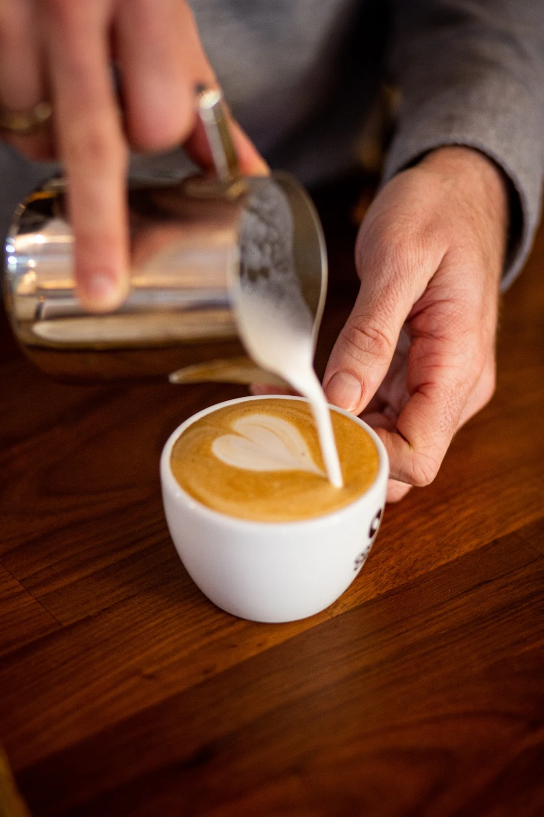 Frisch aufgeschäumte Milch wird im Café wunderbar in einen Cappuccino gegossen